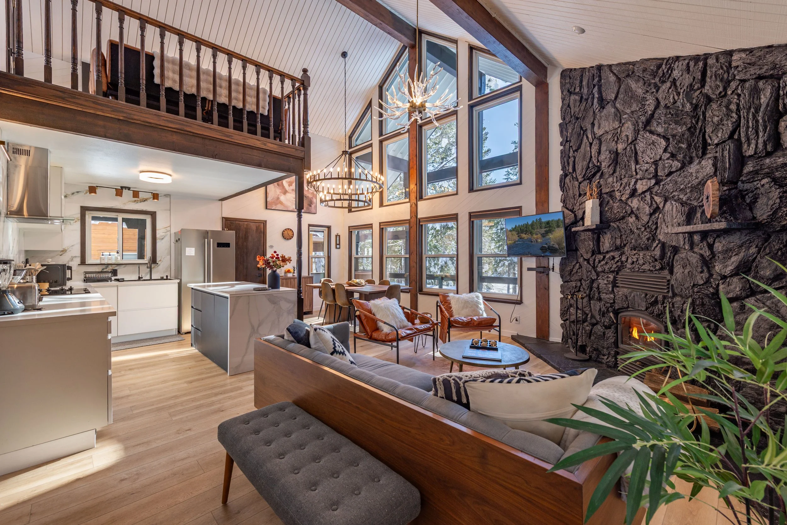 A renovated alpine great room with vaulted ceilings, stone fireplace and walnut detailing